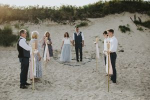 A couple leave their beach wedding in tenby