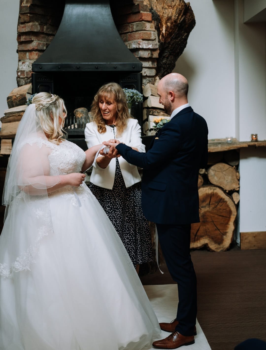 Carmarthenshire bride, groom and celebrant under a pretty floral arch
