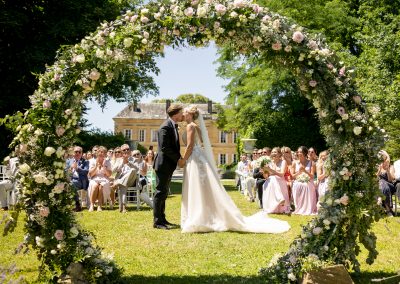 View of bride and groom kissing through flower circle at celebrant led wedding in France